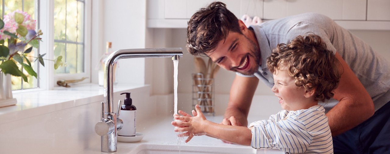 Father Helping Son To Wash Hands With Soap At Home To Stop Spread Of Infection In Health Pandemic