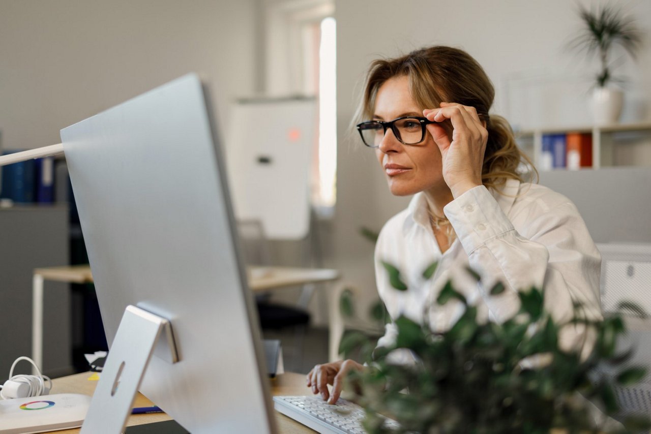 Frau mit Brille sitzt vor Computer