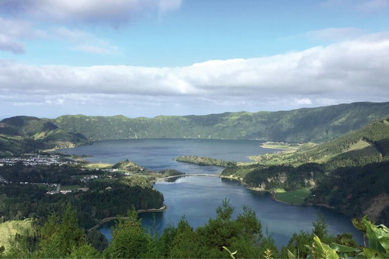 Ein großer See umgeben von Gebirge Landschaft. Blauer Himmel mit einigen Schleierwolken.