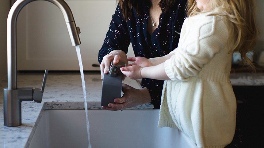 Wasserhahn läuft während Mama und Kind Hände waschen