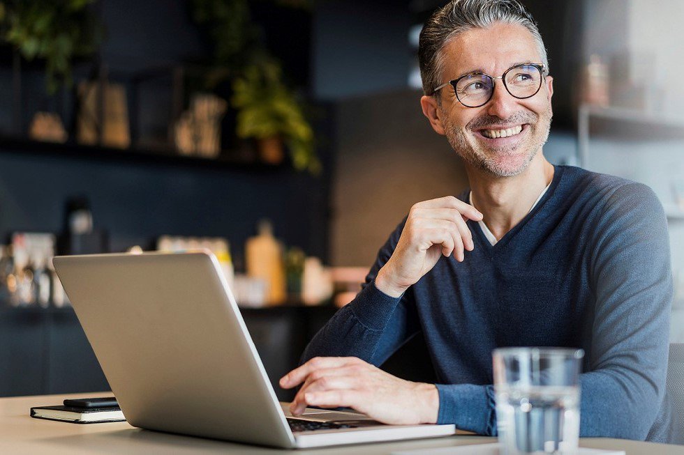 Mann sitzt in der Küche am Laptop