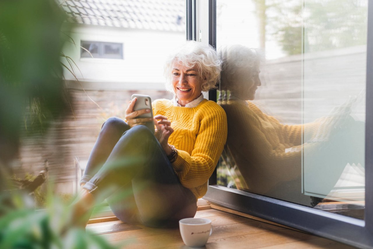 Eine Ältere Frau mit grauem Haar benutzt Fröhlich ihr Handy