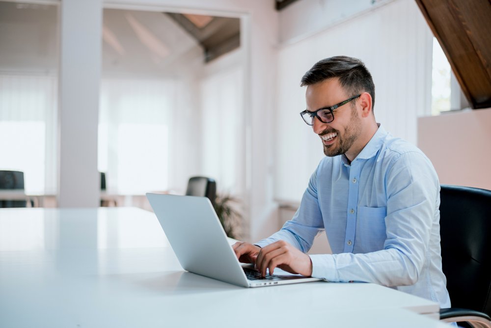 Portrait of young man sitting at his desk in the office; Shutterstock ID 648506098