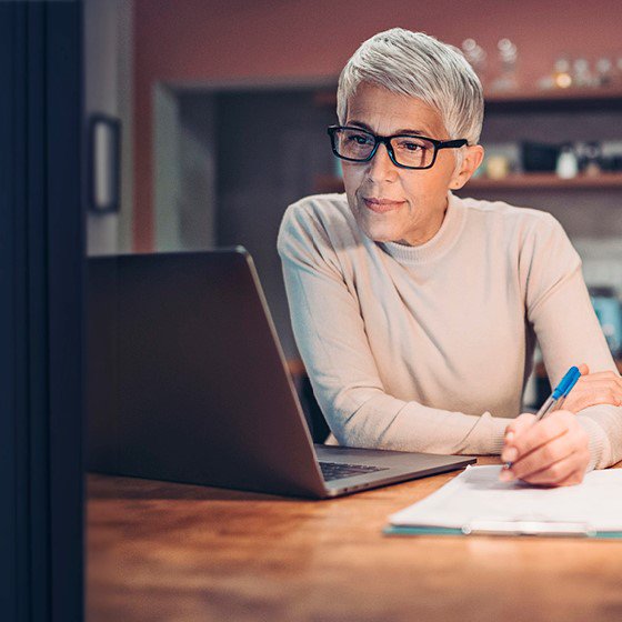 Frau mit Brille sitzt vor Laptop