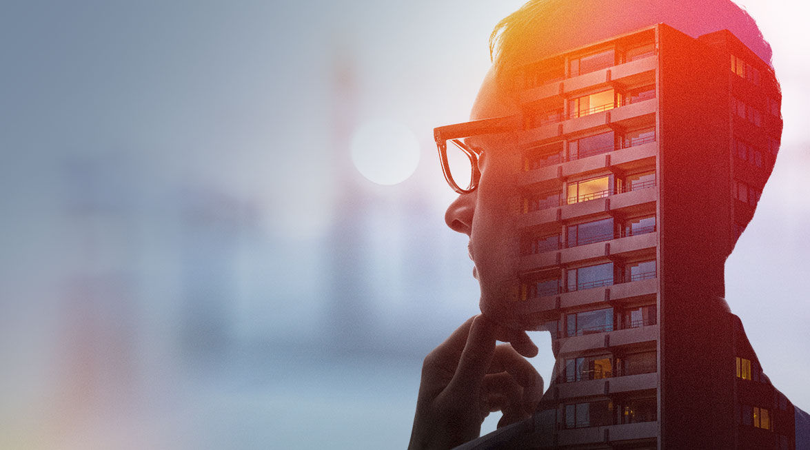 Silhouette eines nachdenklichen Mannes mit Brille, überlagert von einem modernen Wohngebäude