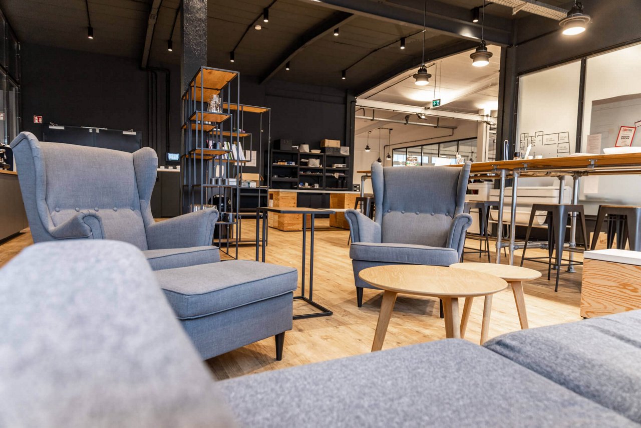 Moderne und gemütliche Sessel sowie ein Sofa in grau stehen in einem offenen Raum