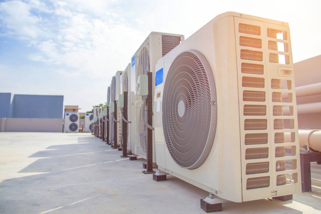 Air conditioning (HVAC) on the roof of an industrial building with blue sky and clouds.