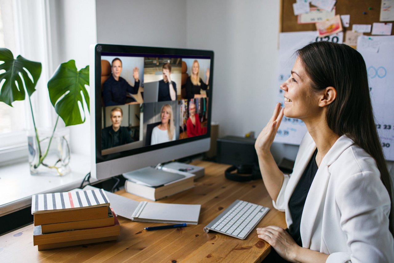 Frau sitzt vor Ihrem Desktop und nimmt an einem Meeting teil